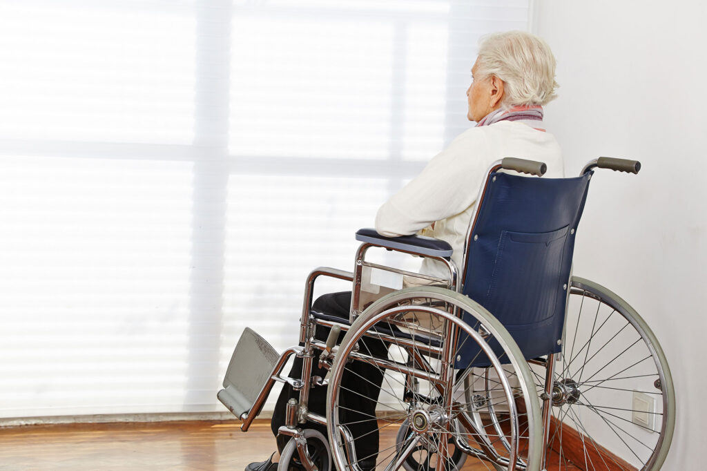 An elderly person sitting in a wheelchair and staring out the window after enduring nursing home abuse in the Philadelphia area